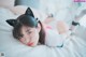 A woman laying on top of a bed wearing cat ears.