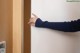 A woman's hand is opening a door with her index finger.