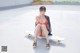 A woman in a bikini sitting on a skateboard.