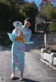 A woman in a kimono holding a fan on a street.