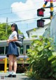 A woman in a school uniform standing next to a train.