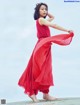 A woman in a red dress standing on a beach.