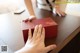 A woman is opening a red box on a table.