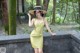 A woman in a yellow dress and a straw hat posing for a picture.