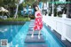 A woman in a red dress standing on the edge of a swimming pool.