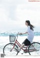 A woman riding a red bike on the beach.