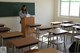 A woman standing at a podium in a classroom.