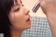 A woman is drinking water from a faucet in a bathroom.